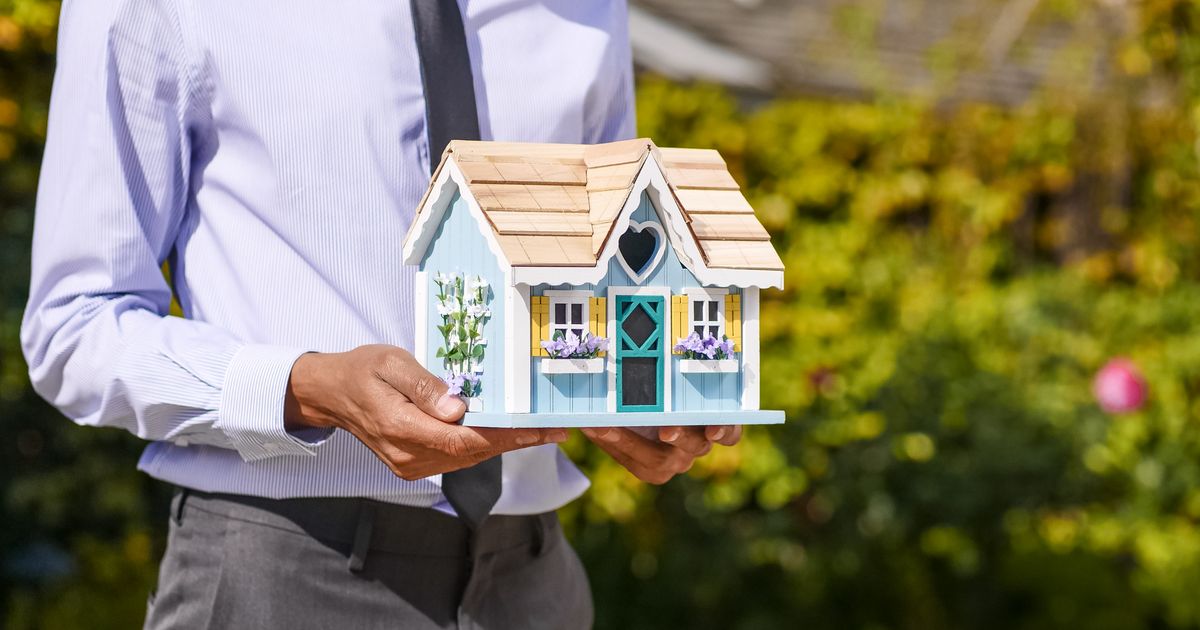 Person holding a small model house