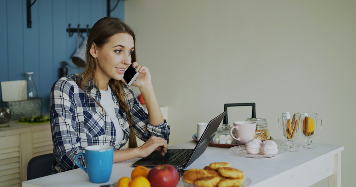 Homeowner on the phone and laptop at her kitchen table