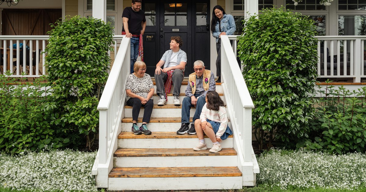 Family sitting on the front porch steps of their home