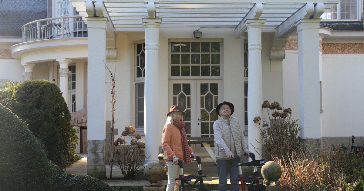 Two older homeowners outside their house